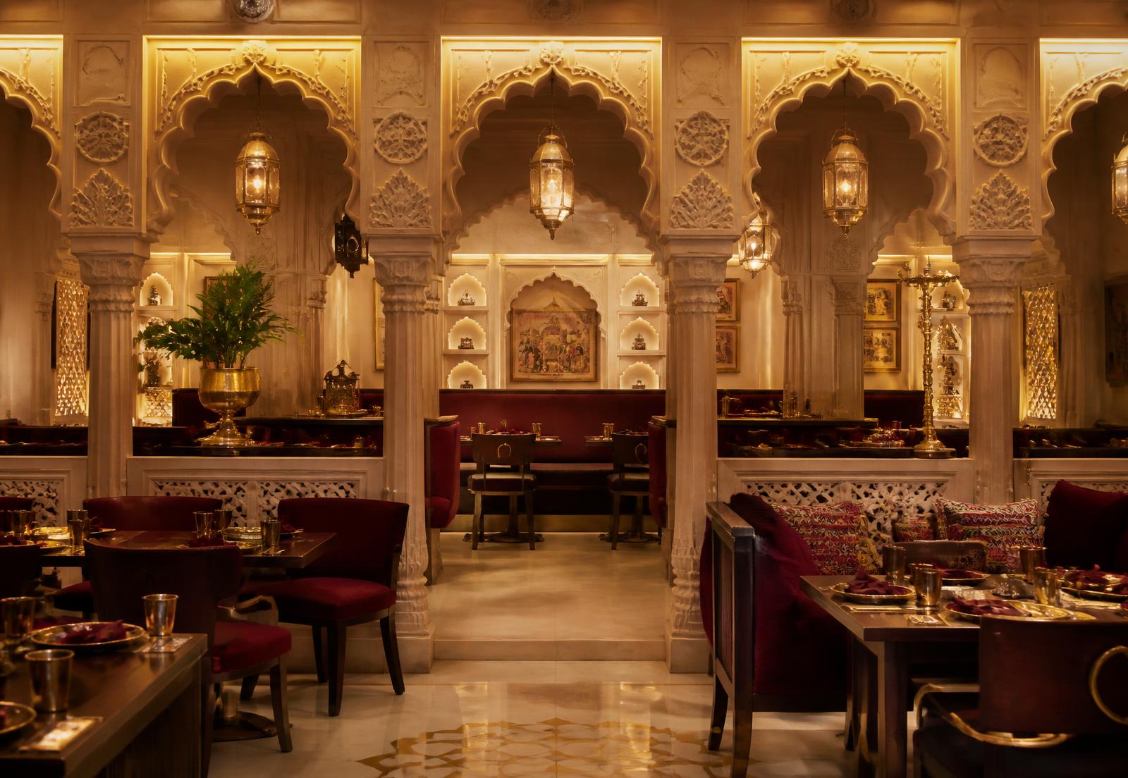 Carved sandstone arches and maroon seating in the dining room